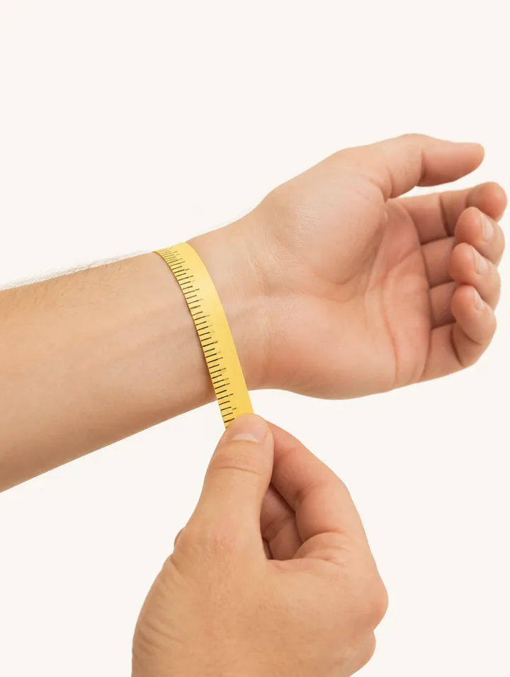 A soft tape measure wrapped snugly around a wrist, just past the wrist bone, where a watch case sits.